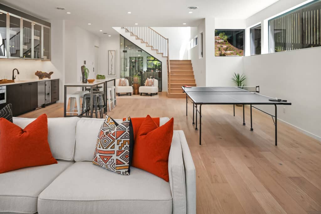 Modern living area with kitchen, sofa, and ping pong table.