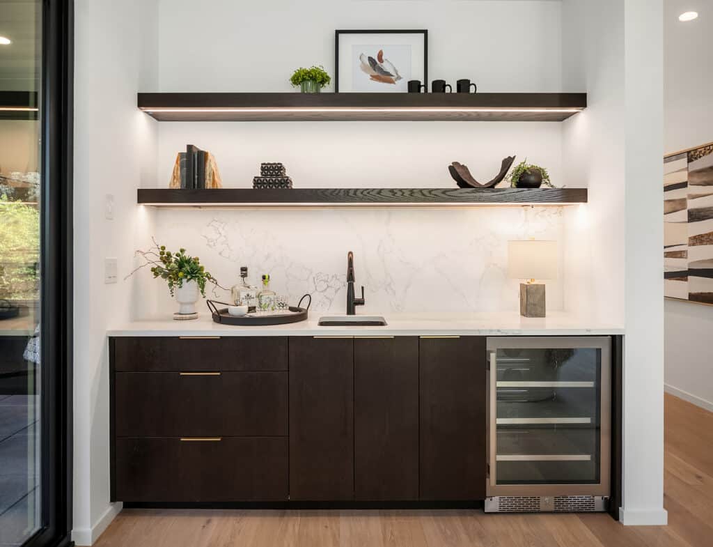 Modern home bar with open shelves and wine fridge.